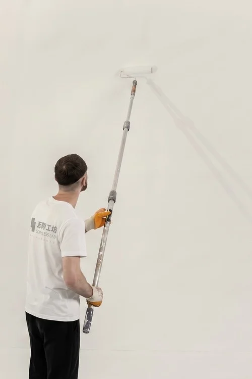 施工师傅用长杆滚筒涂刷墙面